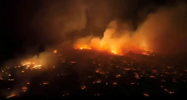 An aerial view of fires burning over the island of Maui, Hawaii, at night