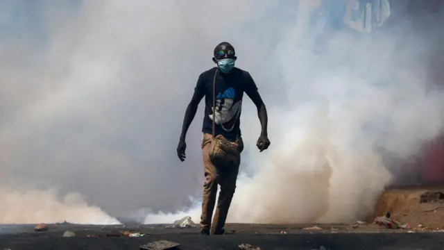 A protester walks amid smoke as supporters of Kenya's opposition leader Raila Odinga of the Azimio La Umoja (Declaration of Unity) One Kenya Alliance, participate in an anti-government protest against the imposition of tax hikes by the government in Nairobi, Kenya July 21, 2023