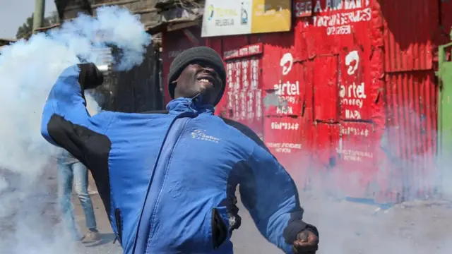 A protester and supporter of the opposition Azimio coalition throws back a teargas canister trown at them as they engage with riot police in running battles, during the third day of renewed nationwide protests in Nairobi, Kenya, 21 July 2023.