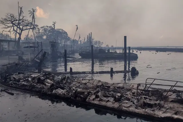 A charred boat lies in the scorched waterfront of Lahaina, Maui island