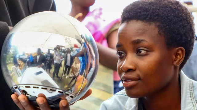 Woman scanning eye with silver sphere