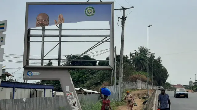 Residents walk past a torn campaign billboard of ousted Gabon President Ali Bongo Ondimba in Libreville on August 31, 2023.