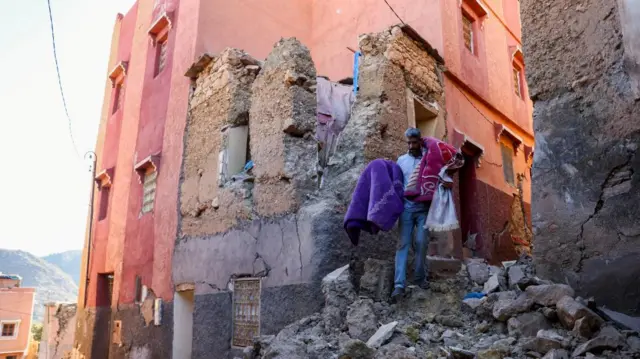 Hussein Adnaie carries belongings out of his damaged house, in the aftermath of a deadly earthquake in Moulay Brahim, Morocco, September 10, 2023