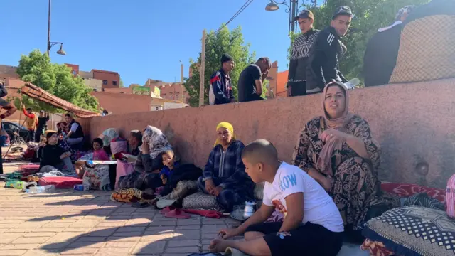 People sit on the street with their belongings