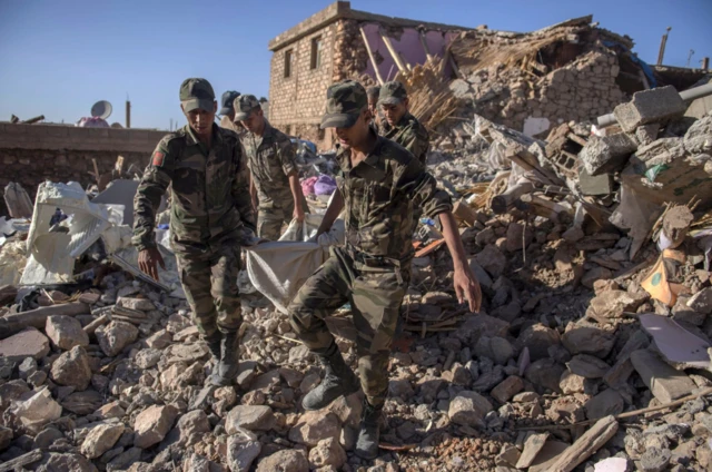 Soldiers carrying corpses from a collapsed building in Tafeghaghte on Saturday