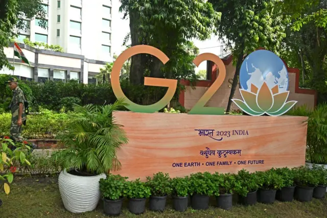 A security personnel walks past the G20 logo installed along a street in New Delhi on September 7, 2023. Special forces, bulletproof cars and men hired to chase away monkeys are among India's elaborate G20 preparations as Prime Minister Narendra Modi readies for a weekend in the global spotlight. (Photo by TAUSEEF MUSTAFA / AFP) (Photo by TAUSEEF MUSTAFA/AFP via Getty Images)