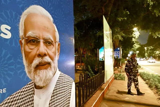 Indian security personnel stand guard next to a G20 communication billboard with a portrait of PM Narendra Modi days ahead of G20 summit in Delhi on September 7, 2023