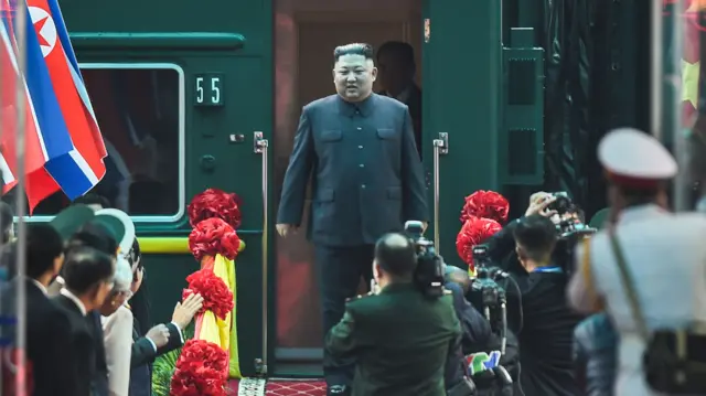 Kim Jong Un walks out of a green train at the Dong Dang railway station