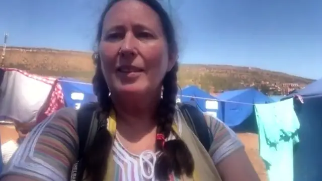 Alice stands in front of blue tents