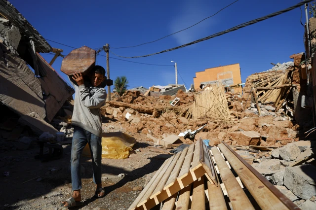 A person carries an item of furniture, in the aftermath of a deadly earthquake, in a hamlet on the outskirts of Talaat N'Yaaqoub, Morocco,