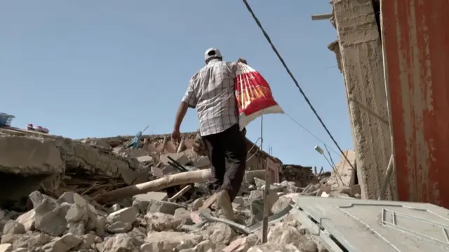 Hamid ben Henna walking through the rubble