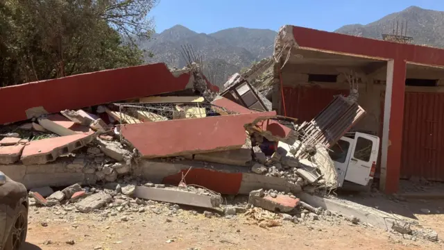 Collapsed garage with van under rubble in Ouirgane village