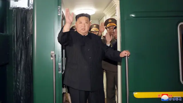 Kim Jong Un waves from a green train as he departs Pyongyang, North Korea