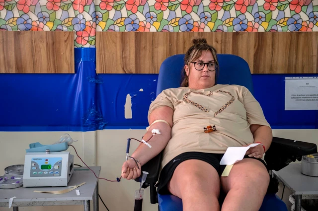 A woman sits inside a blood transfusion centre as she donates blood for the victims of the earthquake