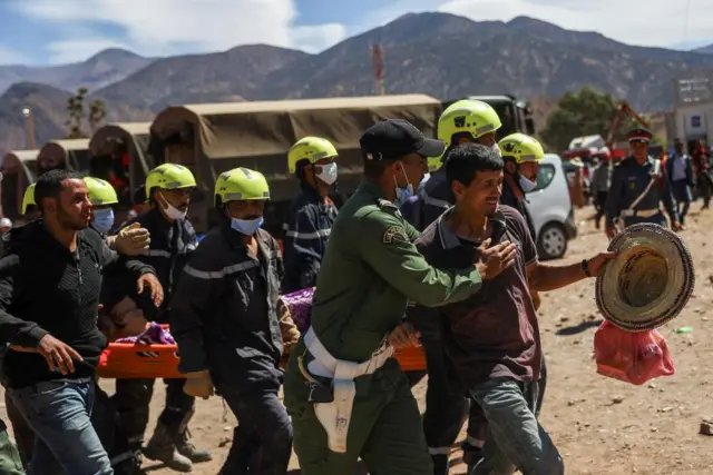 Rescue workers carry away the body of an earthquake victim