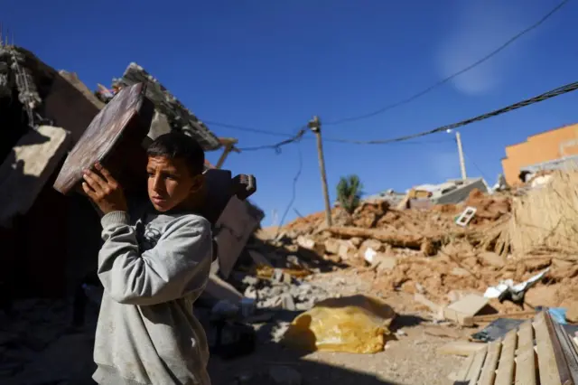 A boy carries an item of furniture in a hamlet on the outskirts of Talat N'Yaaqoub