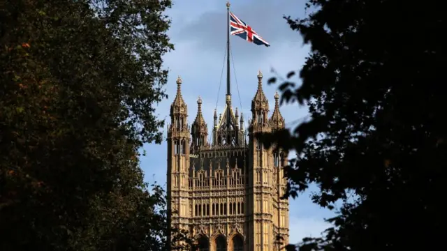 A Union Jack flag on a flag pole above the Houses of Parliament