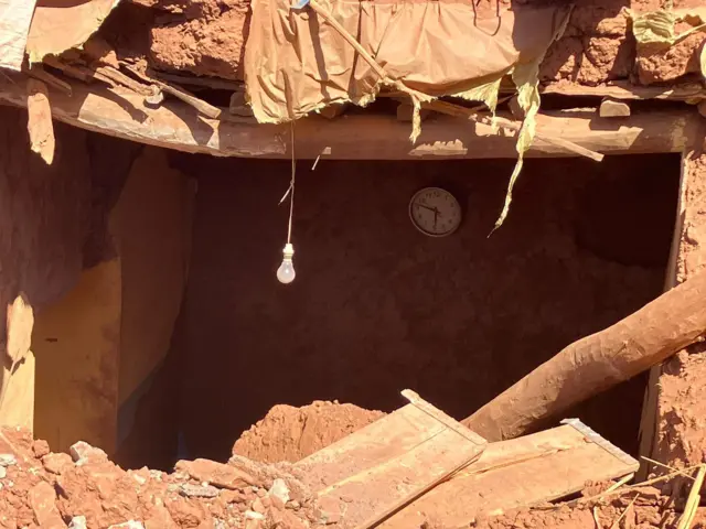 The entry of a house surrounded by rubble