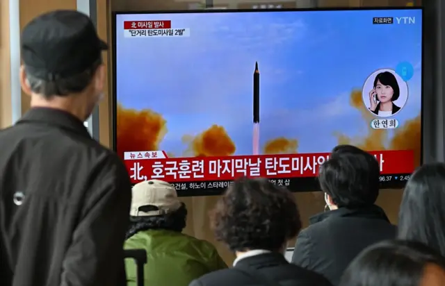 People watch a screen showing a North Korean missile launch