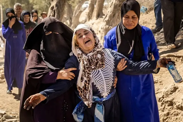 A woman wails and is supported by others after hearing confirmation of her family members' deaths