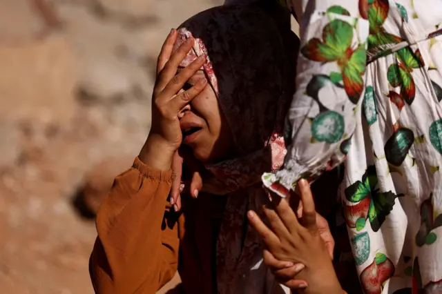 A woman reacts as rescue workers recover one body from the rubble, in the aftermath of a deadly earthquake in Ouirgane, Morocco,