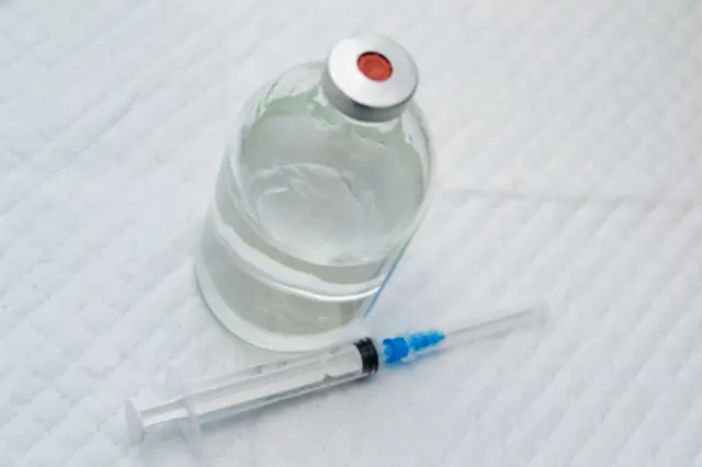 Vial with a clear drug solution and a syringe - stock photo