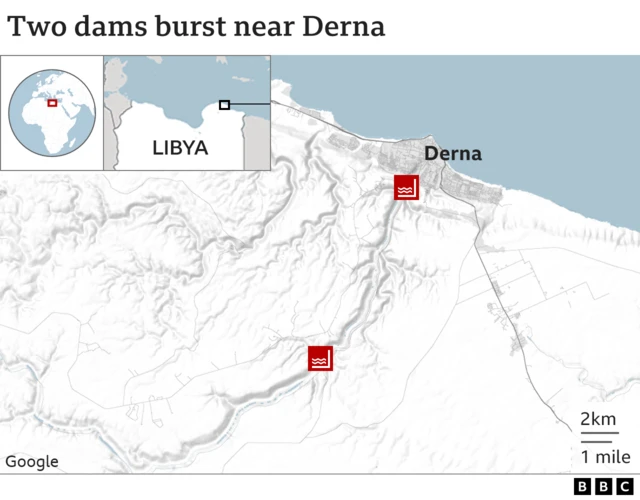 A man shows the locations of two burst dams along the river that bisects Derna