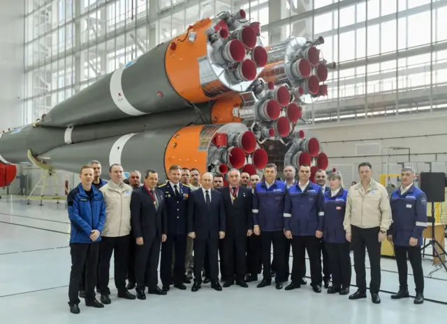 Russian President Vladimir Putin and Roscosmos employees pose for a picture at the Vostochny cosmodrome in front of a rocket in April 2022