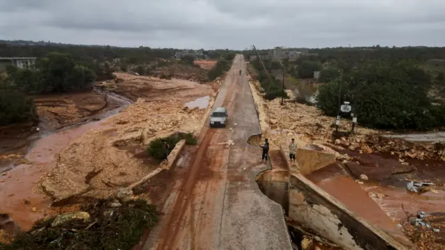 Aerial view of people standing in a damaged road as a powerful storm and heavy rainfall hit Shahhat city, Libya, September 11, 2023.