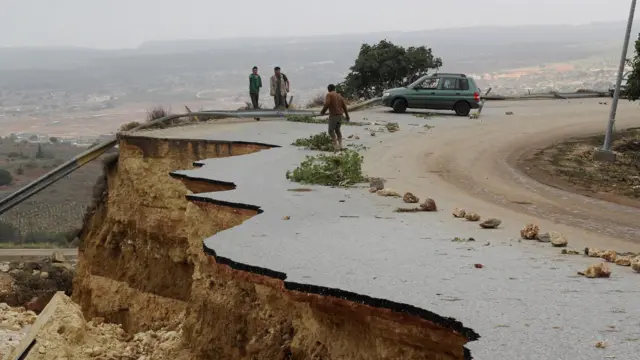 People stand in a damaged road as a powerful storm and heavy rainfall flooded hit Shahhat city, Libya, September 11, 2023. REUTERS