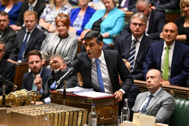 Sunak, standing at the dispatch box, gestures towards the opposition in the House of Commons