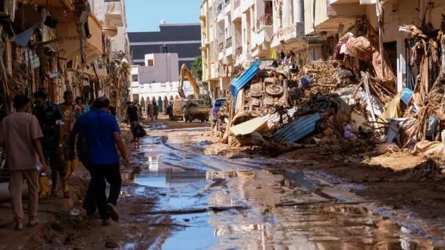 People walk in the mud between the rubbles, after a powerful storm and heavy rainfall hit Libya, in Derna, Libya September 13, 2023.