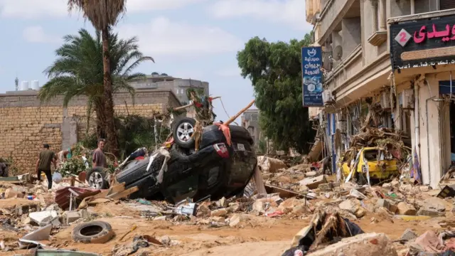 A man stands next to a damaged car, after a powerful storm and heavy rainfall in Derna, Libya - 12 September 2023