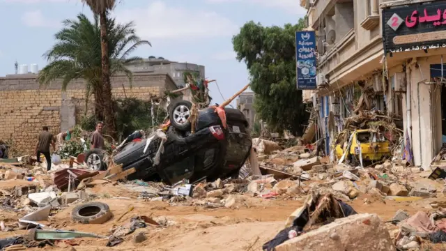 An upturned car among a huge amount of debris on a street in Derna