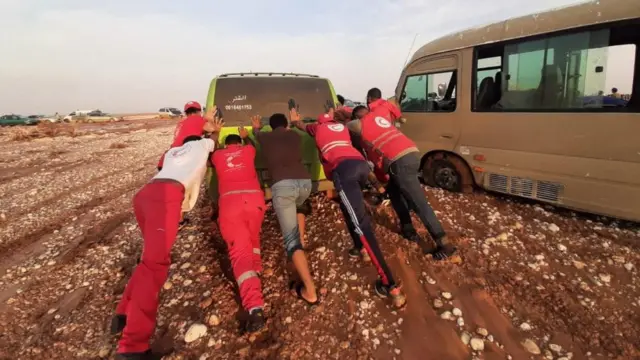 Members of Libyan Red Crescent push a truck through the mud in an area affected by flooding in Libya