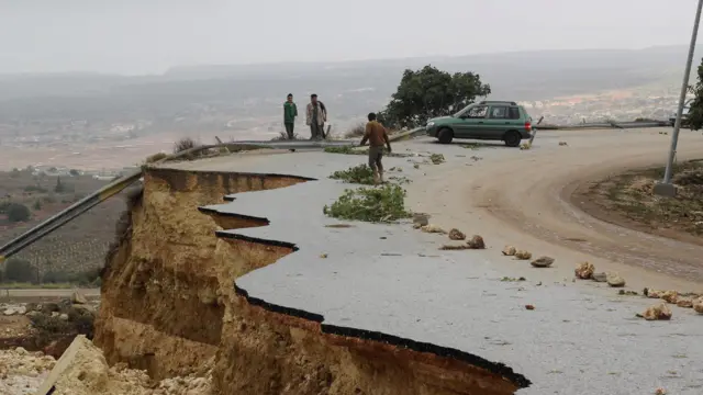 eople stand in a damaged road as a powerful storm and heavy rainfall flooded hit Shahhat city, Libya, September 11, 2023. REUTERS