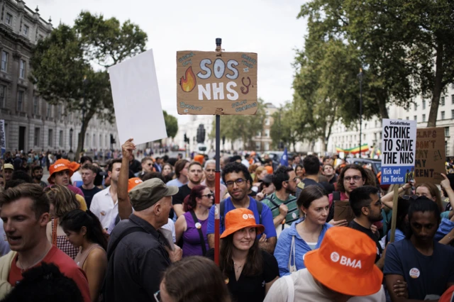 A protestor holds up a sign that reads 'SOS NHS' at the junior doctors' strike in August