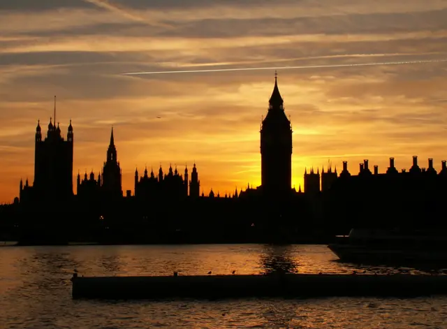 A silhouette of the UK houses of parliament in front of a sunset