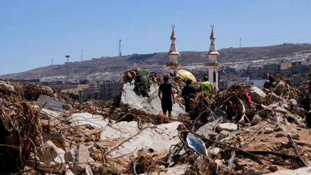 People walk amidst the debris, following a powerful storm and heavy rainfall hitting the country, in Derna, Libya September 13, 2023.