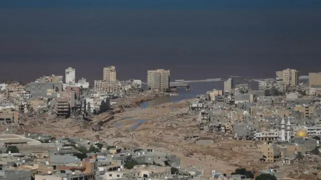 Aerial view of Derna, with a large path of collapsed and damaged buildings following the river's course to the sea