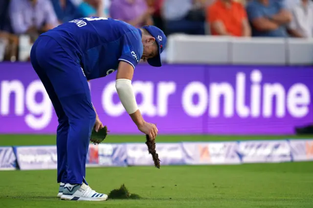 England's David Willey replaces a divot of grass during the fourth Metro Bank One Day International match at Lord's, London