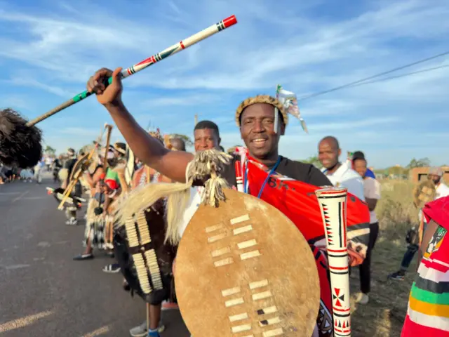 Zulu men chanting while holding shields and maces.