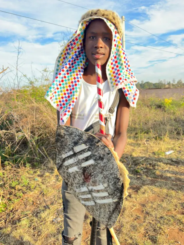 A young Zulu boy holding a shield.