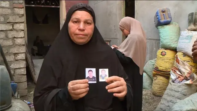 Raya Faisal holds up images of her sons who are missing following the floods in Libya