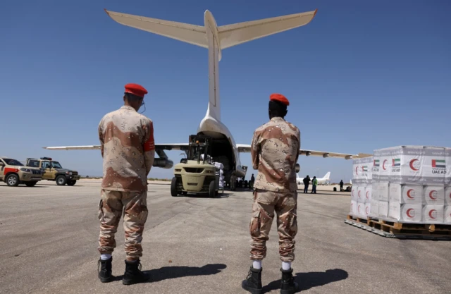 Libyan military officers monitor the aid workers from the UAE unloading relief items at Benina Airport in Benghazi - 15 September 2023