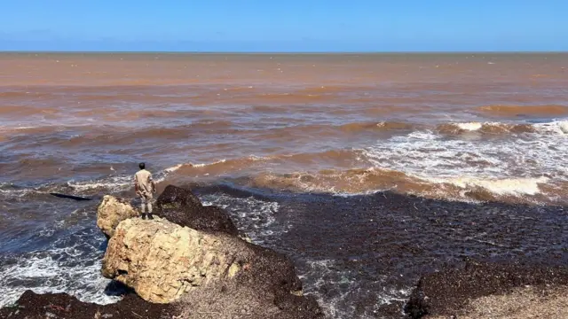 A man stands on a rocky outcrop looking over the sea in Derna 14 September 2023