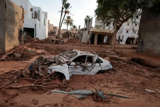 A destroyed car submerged in mud in Derna