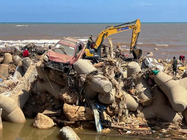 A mna operates a digger while searching for bodies in Libya