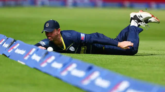 Ian Holland dives to stop a boundary