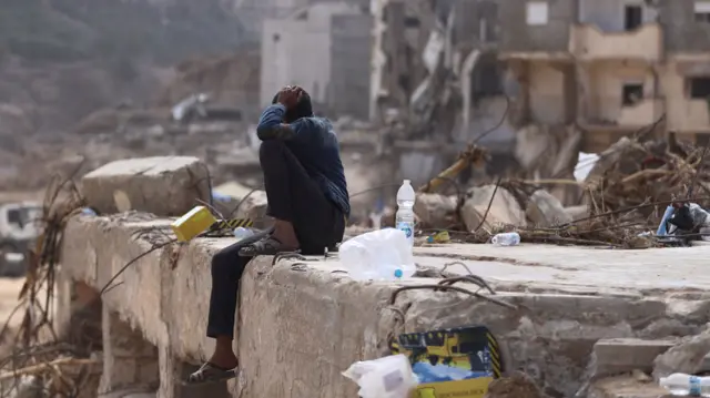 A man sits on rubble caused by fatal floods in Derna, Libya, 18 September, 2023.